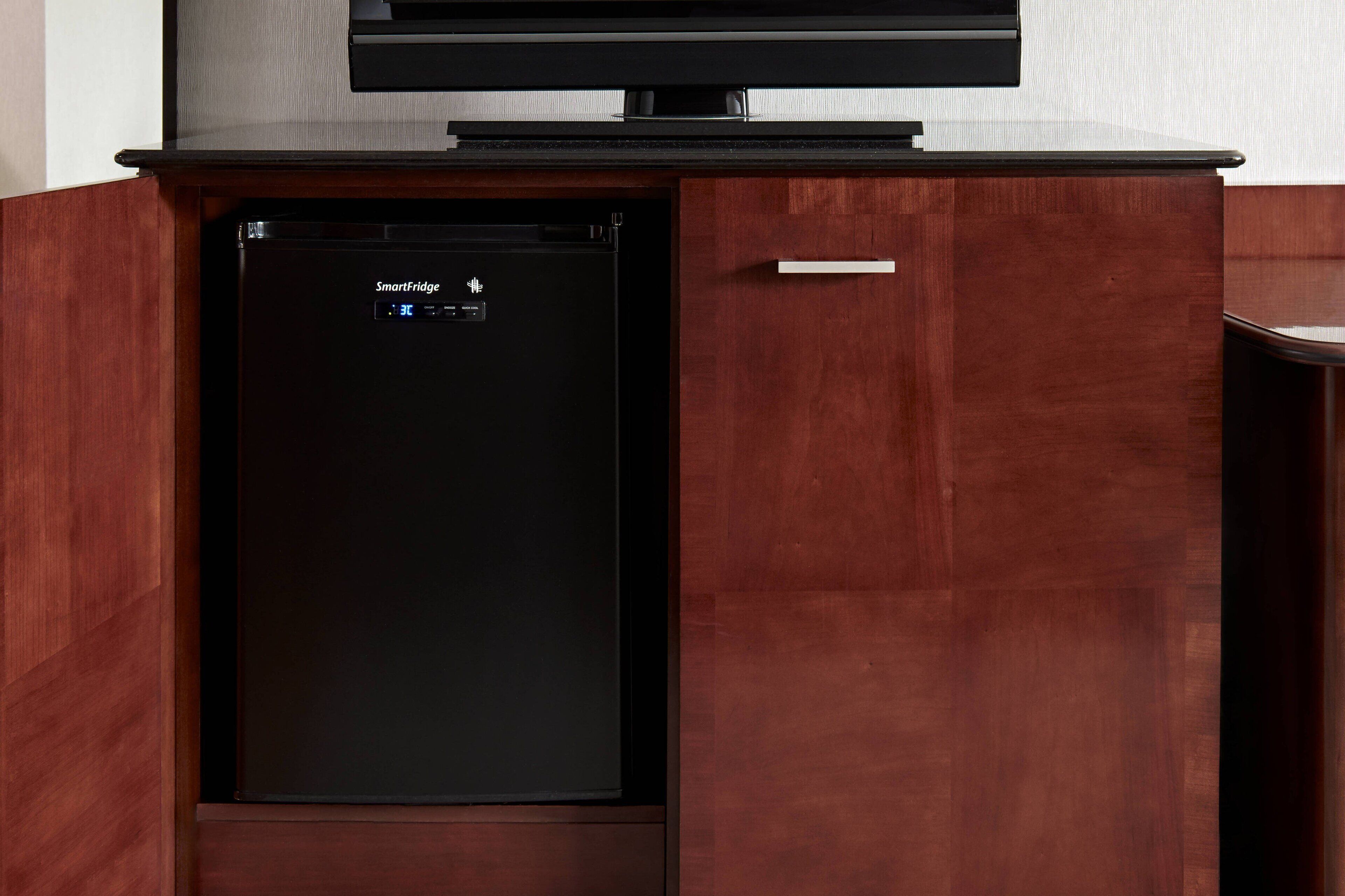 A compact kitchen with a built-in dishwasher and a flat-screen TV mounted above it.