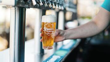 Une main tenant un verre de bière dans un bar doté de plusieurs robinets.