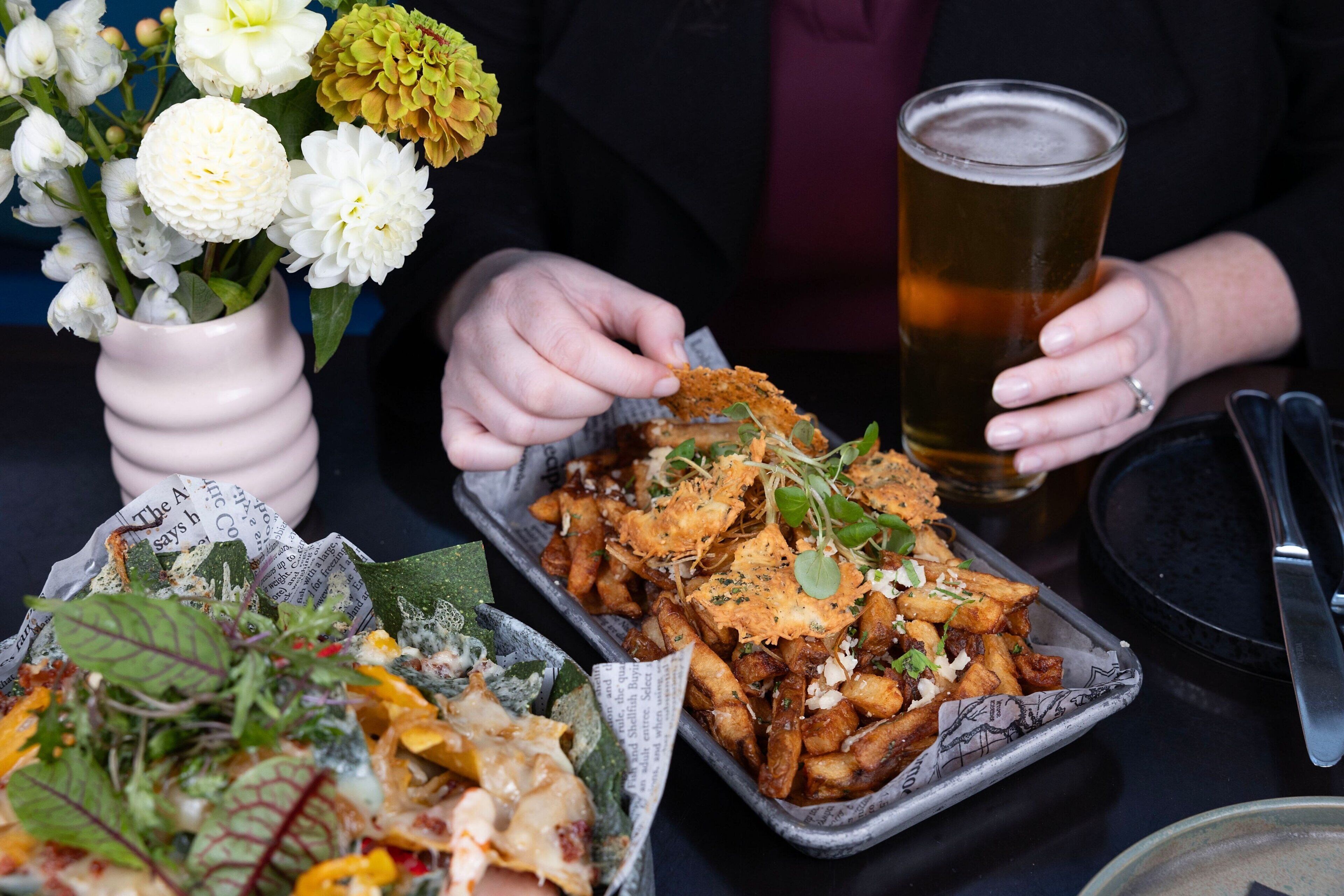A dining table with a meal consisting of fries, a salad, and a drink.