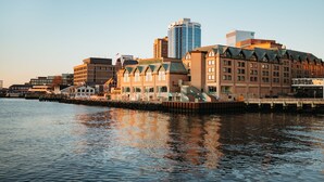 A waterfront hotel with a modern building and traditional architecture, featuring a dock and a clear view of the water.