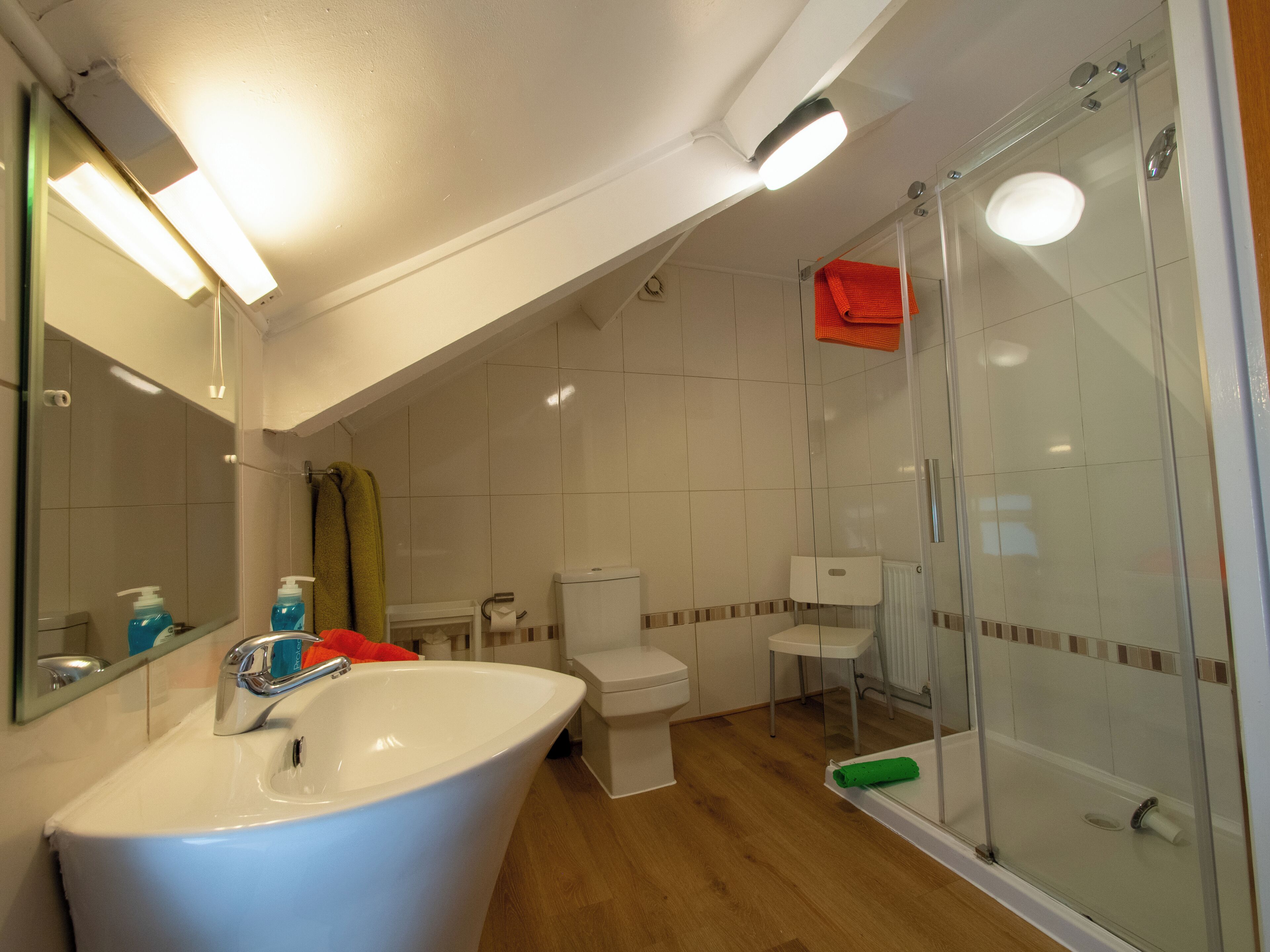 Une salle de bain moderne avec un lavabo blanc, une douche à parois de verre et des toilettes.