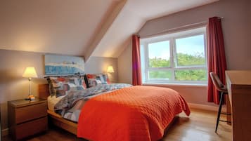 Une chambre à coucher avec un lit, deux lampes de chevet, un tableau au mur, une fenêtre avec des rideaux et un plancher en bois.