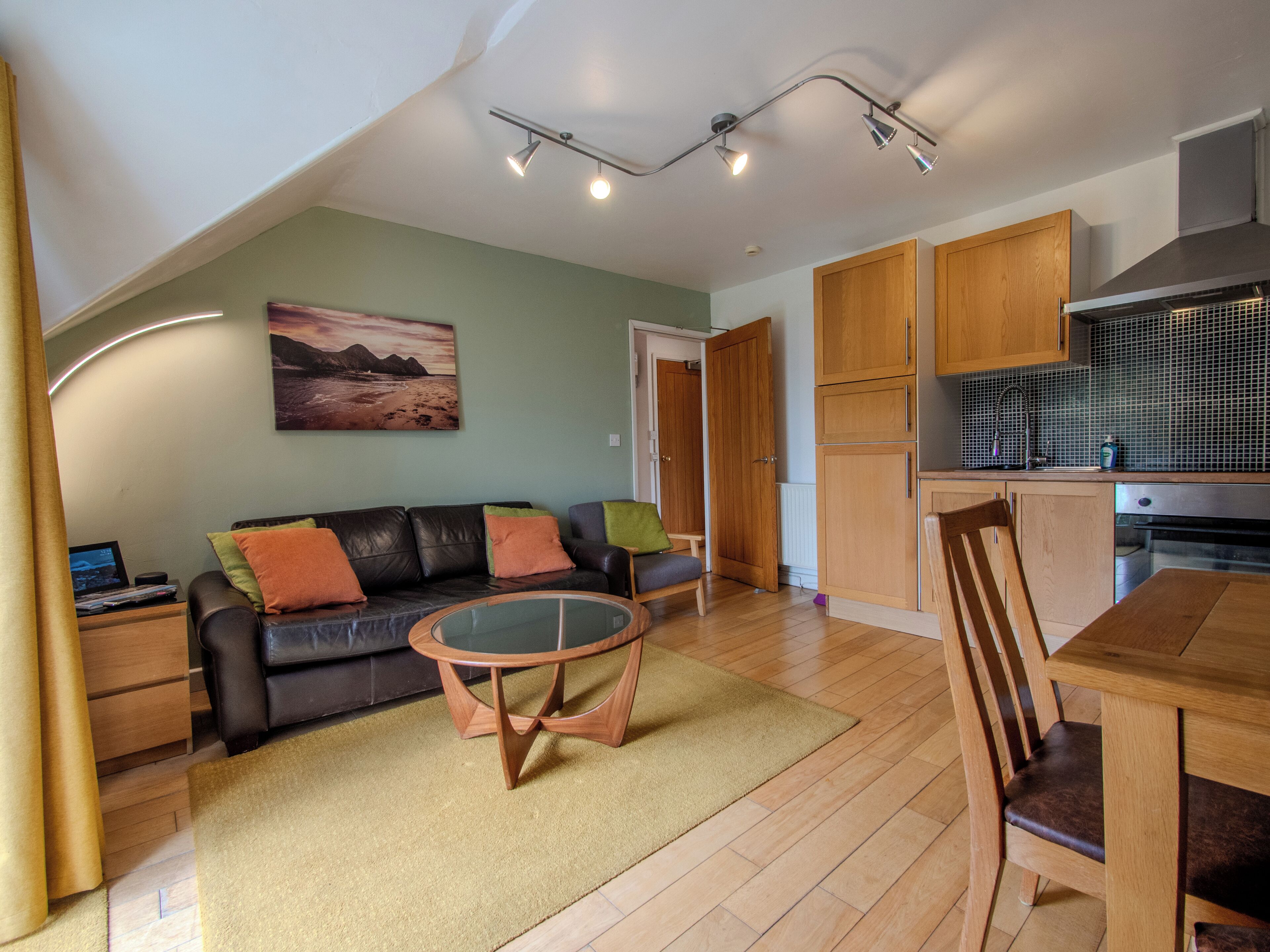 Un espacio habitable compacto con sofá, mesa de centro, mesa de comedor y zona de cocina.