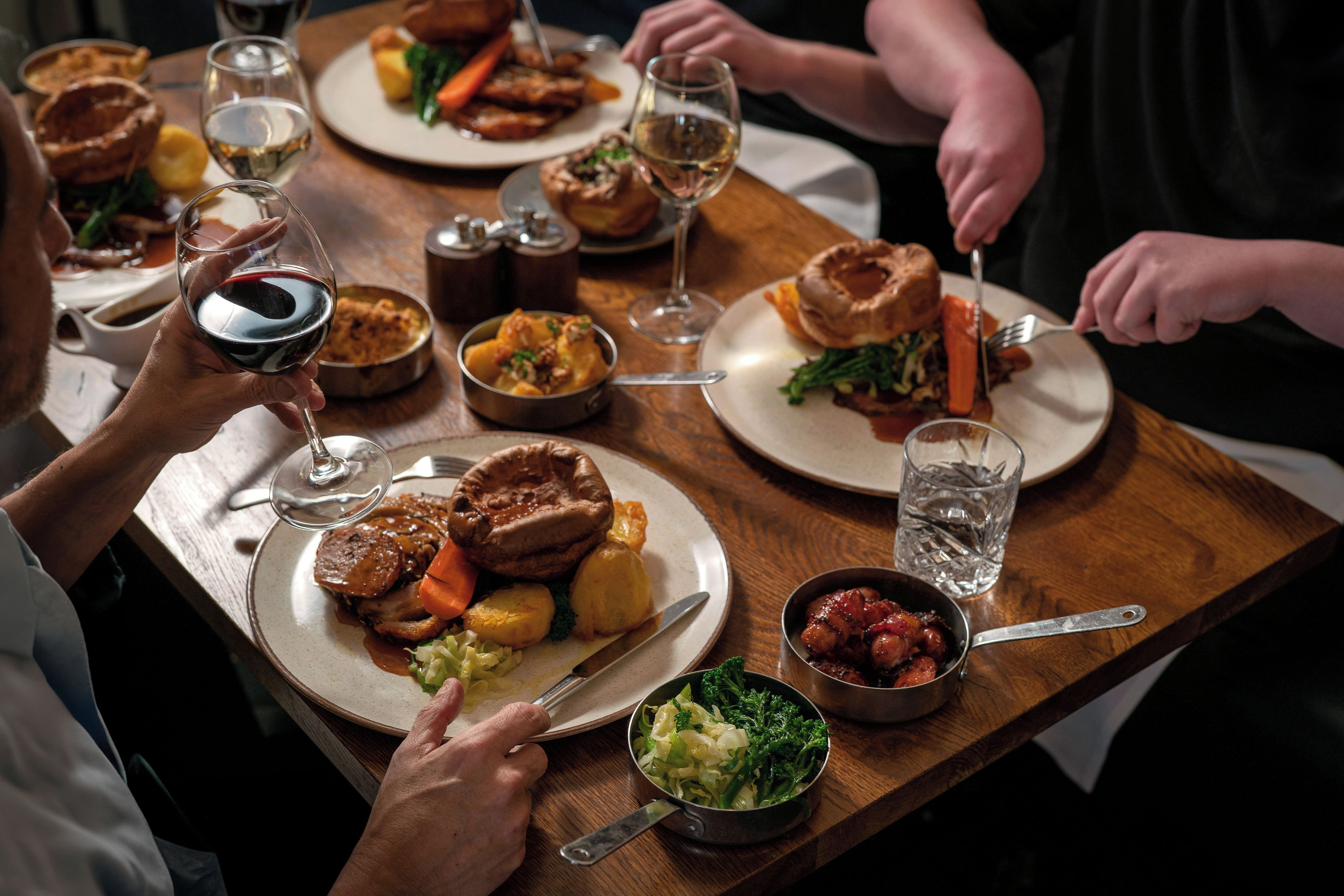 Une table à manger avec des assiettes remplies de nourriture, des verres de vin et une variété de plats.