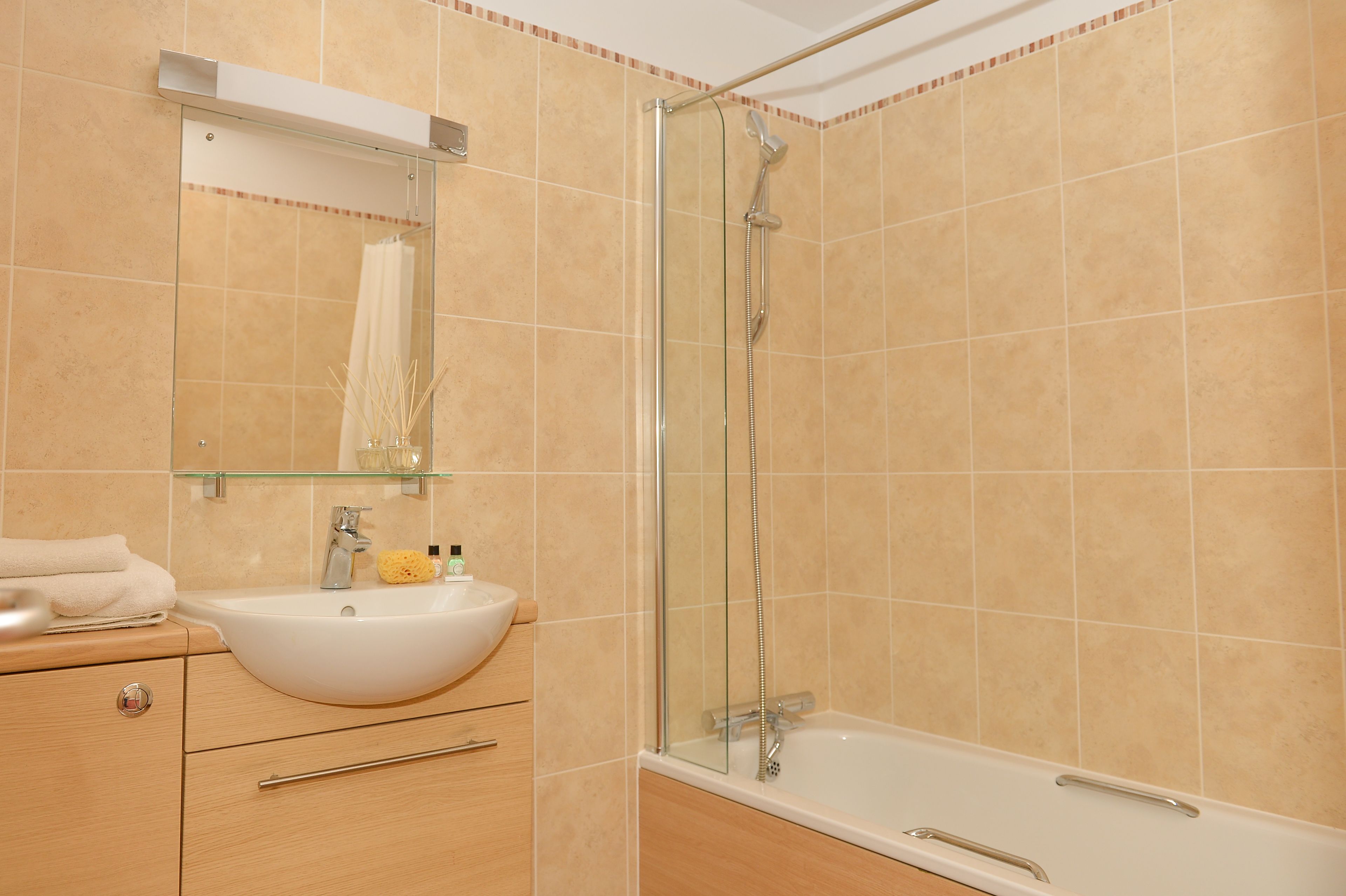 A bathroom with a glass-enclosed shower, a white sink, and a mirror above it.