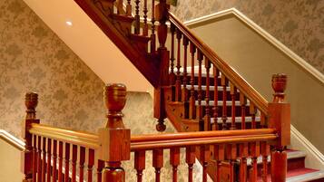 A wooden staircase with a handrail and balusters, leading to a landing with a carpeted floor.