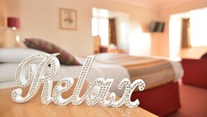 A hotel room with a bed, a red armchair, and a sign that reads "Relax". - Wherry Hotel (Lowestoft)