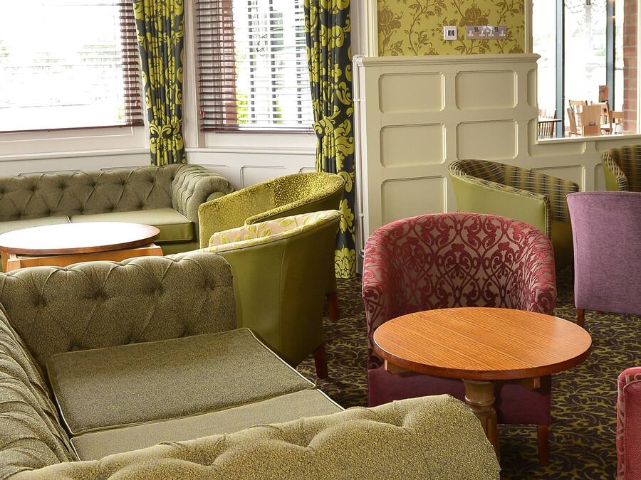 A room with a green sofa set, a round wooden table, and a patterned armchair.
