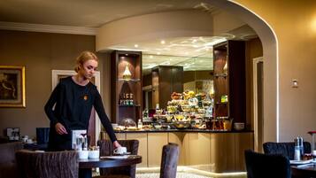 Un hall d’hôtel comprenant un bar, des espaces pour s’asseoir et un buffet.