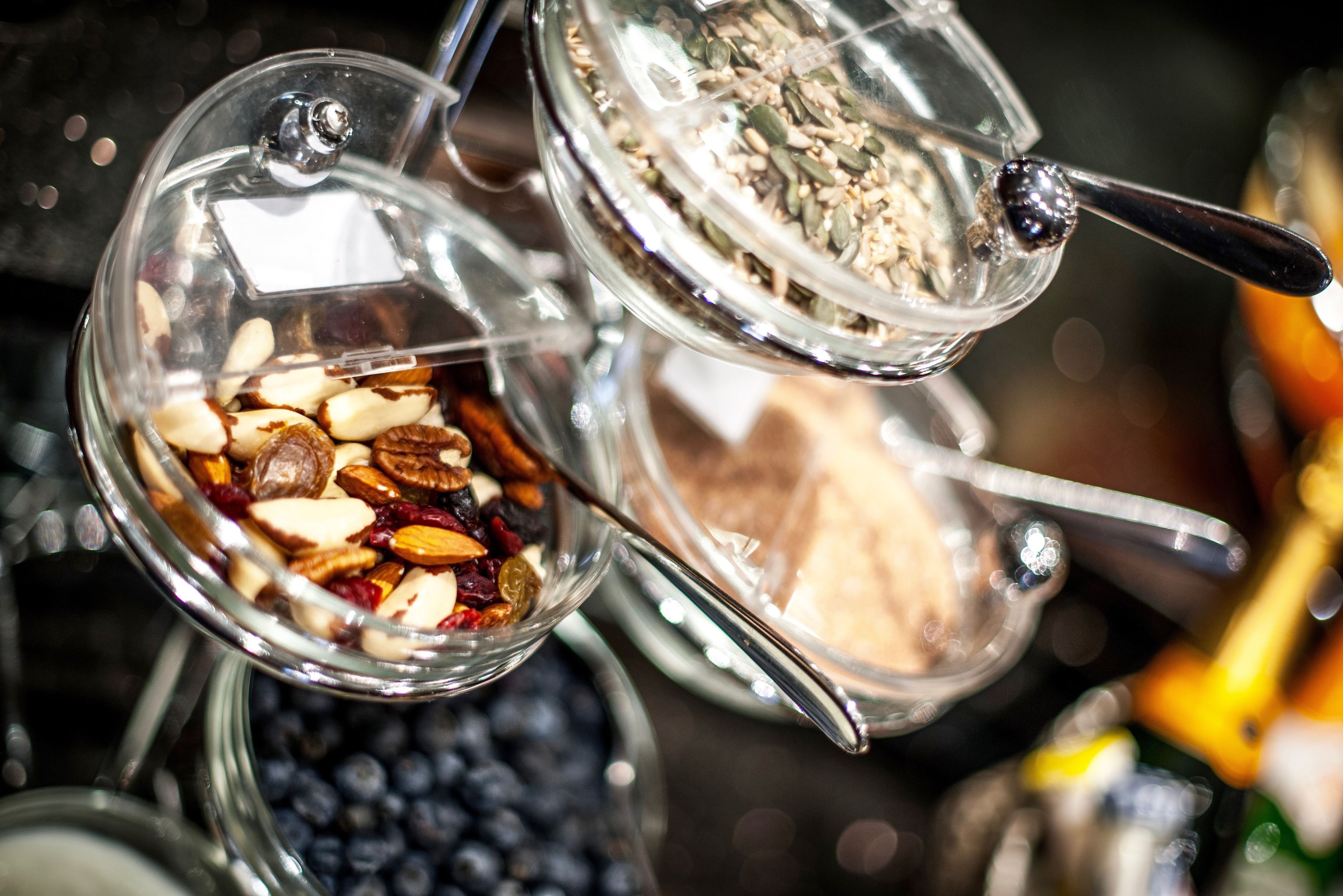 Three glass containers with lids, each filled with different types of nuts and seeds.