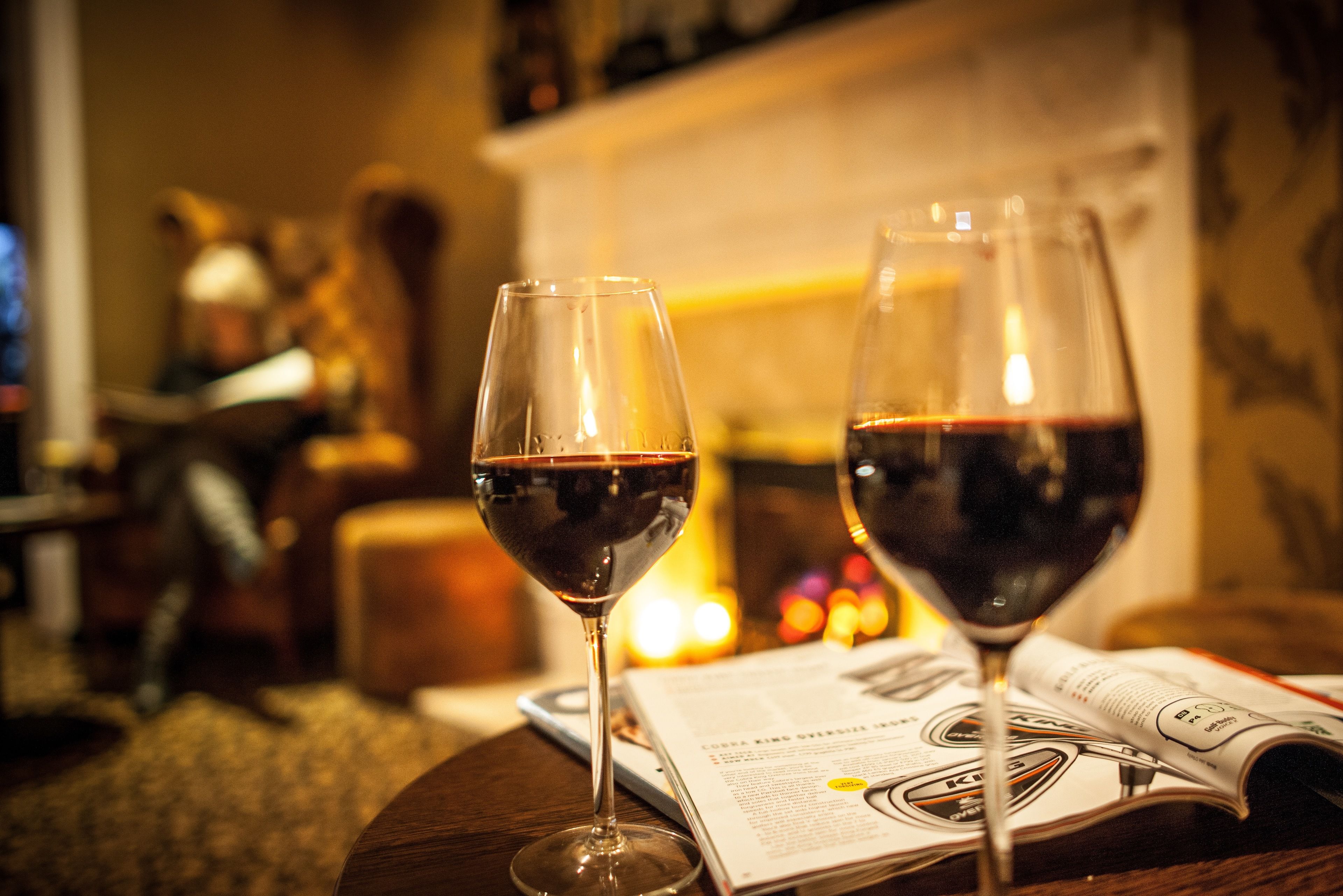 Two wine glasses on a table with a magazine.