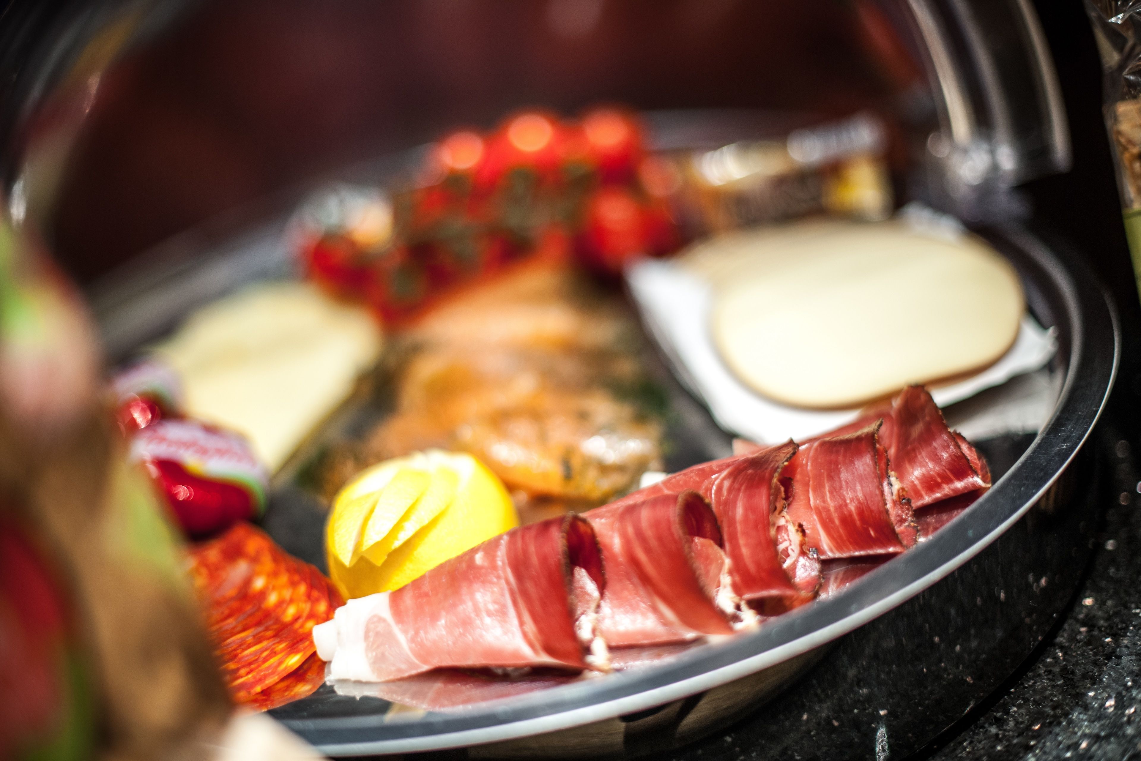 A charcuterie board with various meats, cheeses, and fruits.