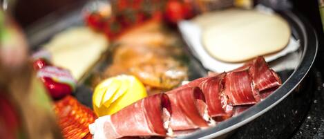 A charcuterie board with various meats, cheeses, and fruits.
