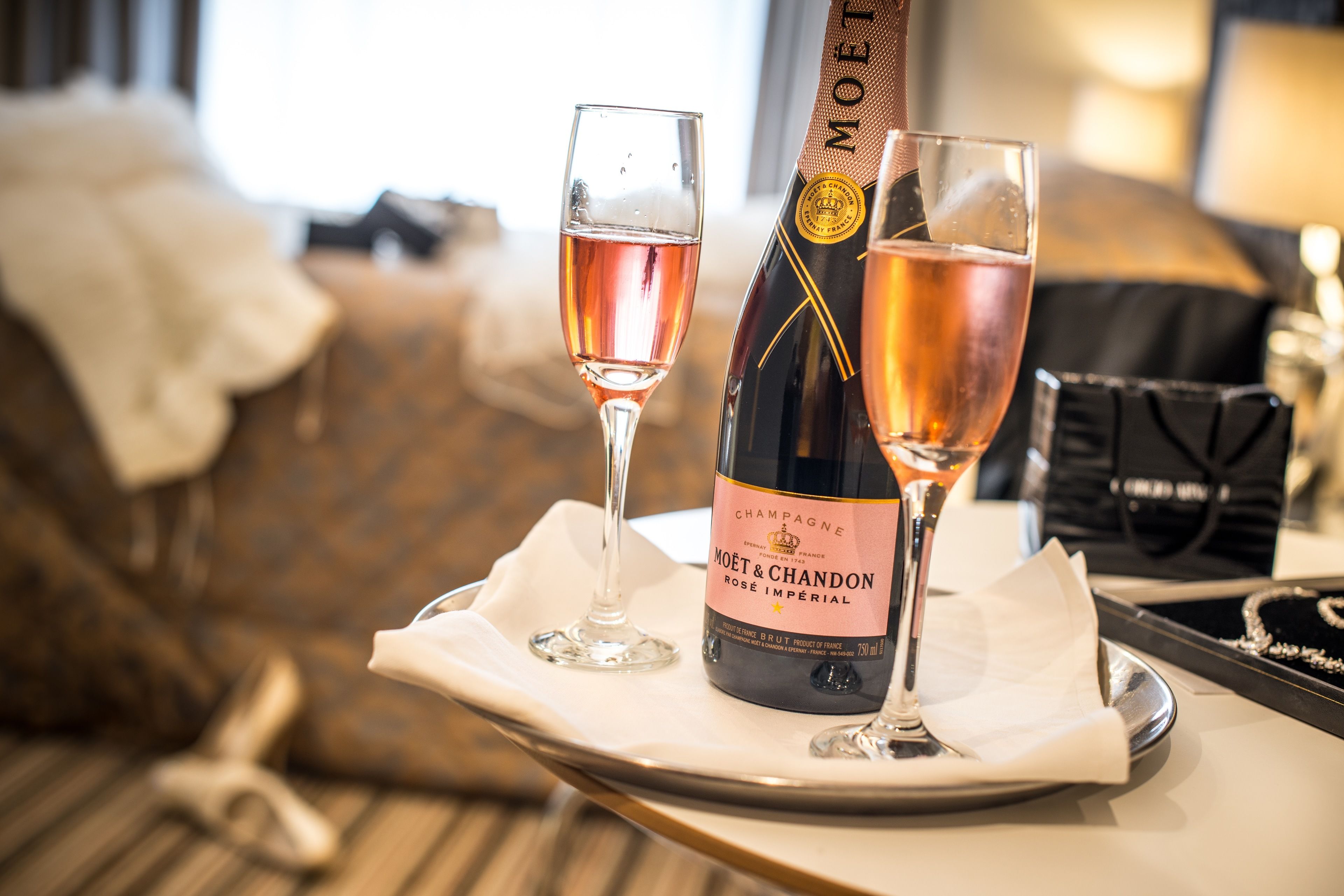 Una botella de champán Moët & Chandon y dos vasos de vino rosado sobre una bandeja.