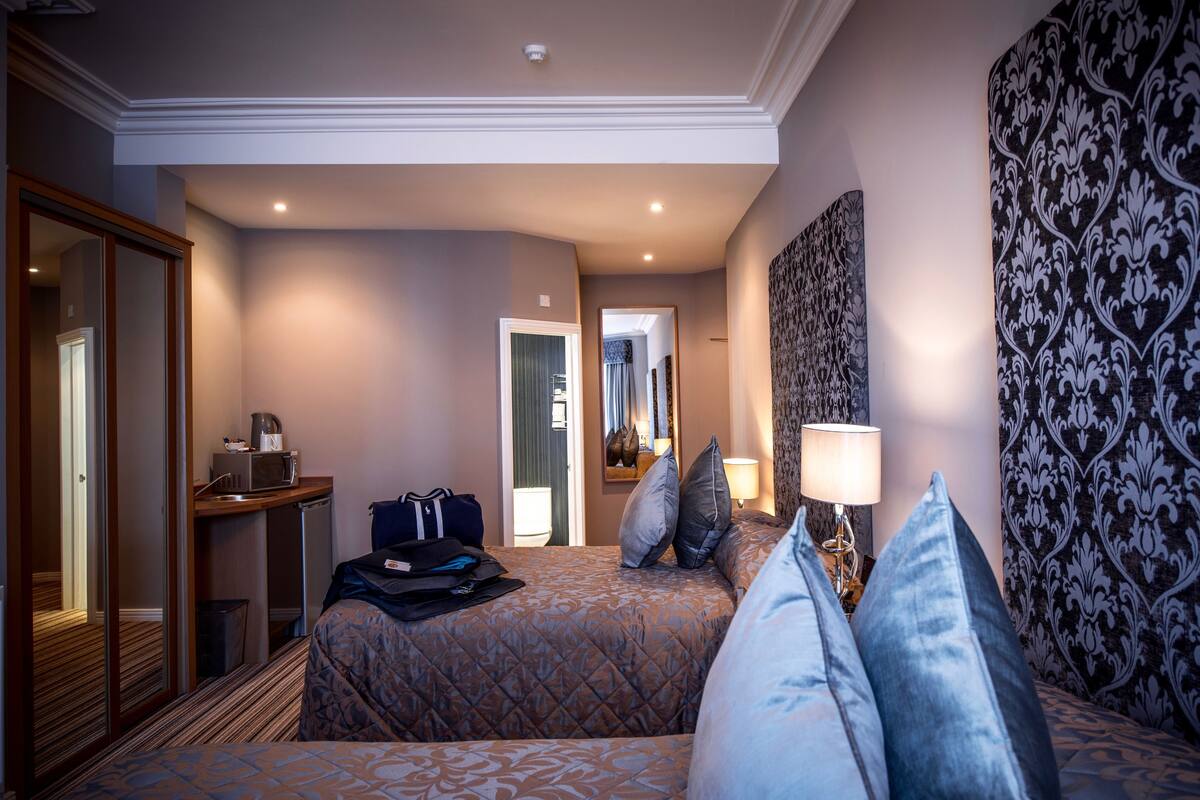 A hotel room with a bed, bedside table, lamp, and a mirror.