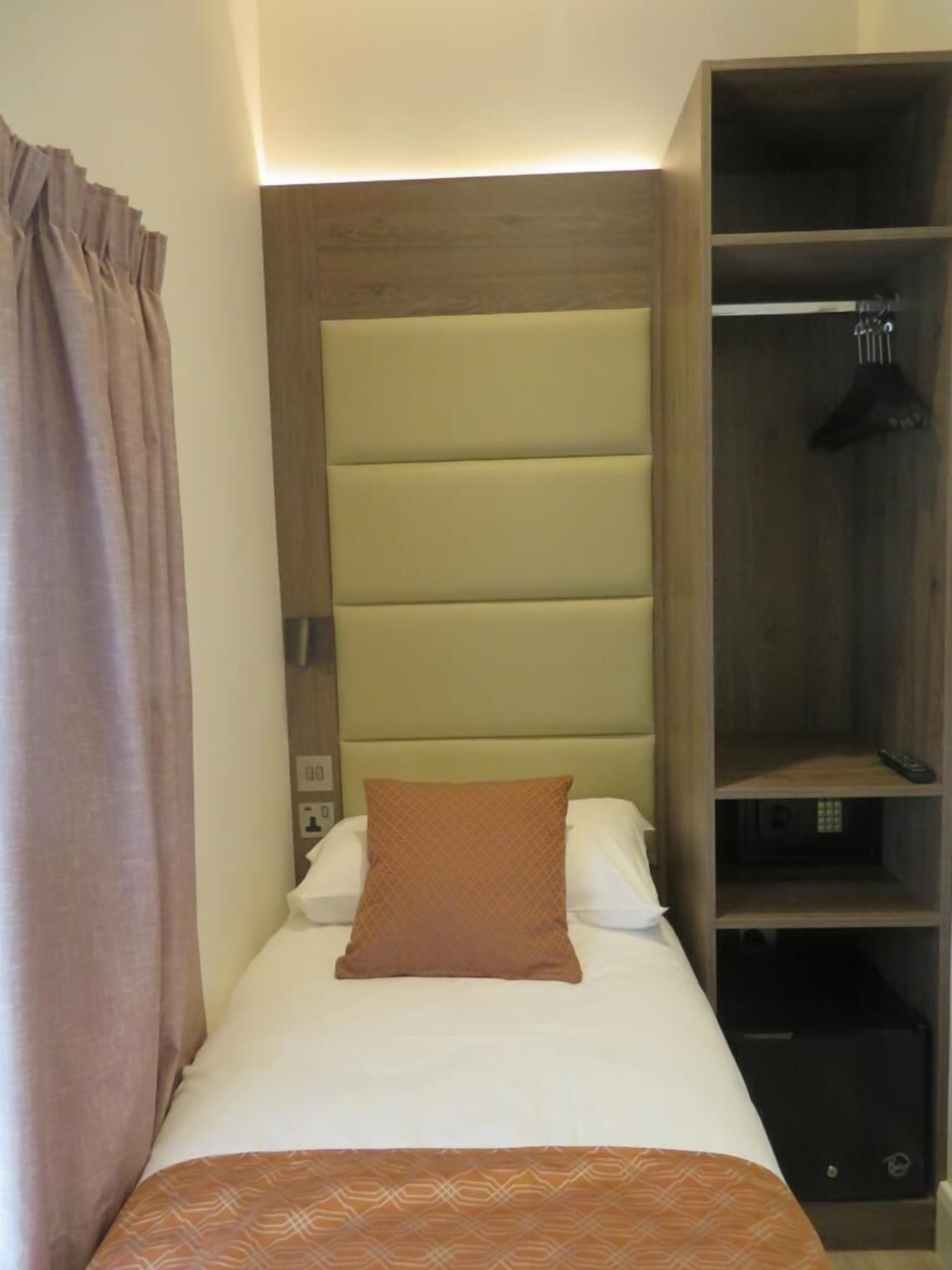 A single bed with a headboard, a bedside table, and a wardrobe with hanging space.