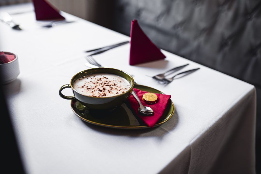 Een tafel gedekt met een kop koffie, een lepel en een servet op een tafel met een witte tafelkleed.
