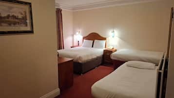 A hotel room with two beds, a bedside table, a nightstand, a lamp, and a framed picture on the wall.