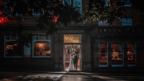 A couple kissing in front of a building with a sign that reads "Borough Arms Hotel." - Borough Arms Hotel (Newcastle-Under-Lyme)