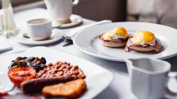 Una mesa de desayuno con platos de huevos benedictinos y una variedad de acompañamientos.