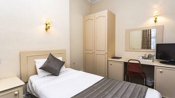 A hotel room with a bed, a desk with a chair, a wardrobe, and a television.