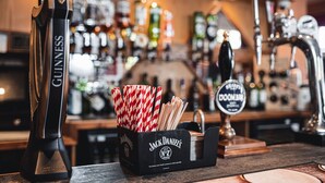 A bar counter with a Guinness beer tap, a Jack Daniel's bottle, and a sign for the bar. - Borough Arms Hotel (Newcastle-Under-Lyme)