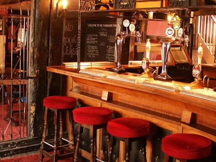 A bar with wooden stools and a chalkboard menu.