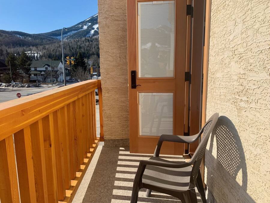 A balcony with a wooden railing, a chair, and a door with two windows.