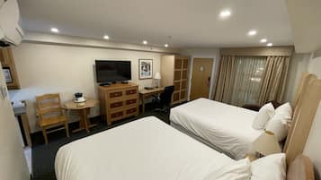 Una habitación de hotel con dos camas, un escritorio, un televisor y un armario.