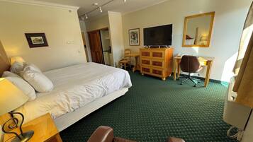 A hotel room with a bed, a desk, a chair, a dresser, a television, and a mirror.
