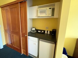 A compact kitchenette with a microwave, coffee maker, and a small refrigerator.