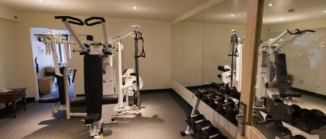 A gym with exercise equipment, a mirror, and a carpeted floor.