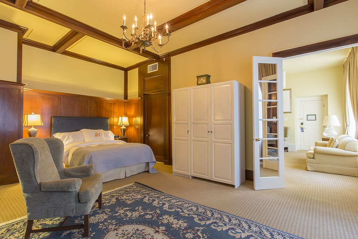 Habitación de hotel con una cama grande, una silla, un armario y una araña.
