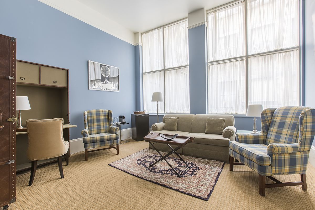 Una sala de estar con pared azul, un sofá, dos sillones, una mesa de centro y una alfombra.
