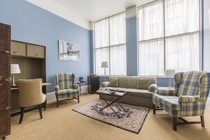 A living room with a blue wall, a sofa, two armchairs, a coffee table, and a rug.