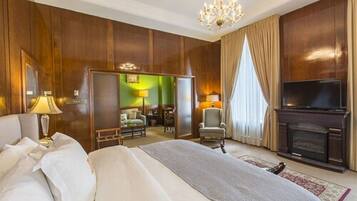 A hotel room with a large bed, a TV, a fireplace, and a view of the city.