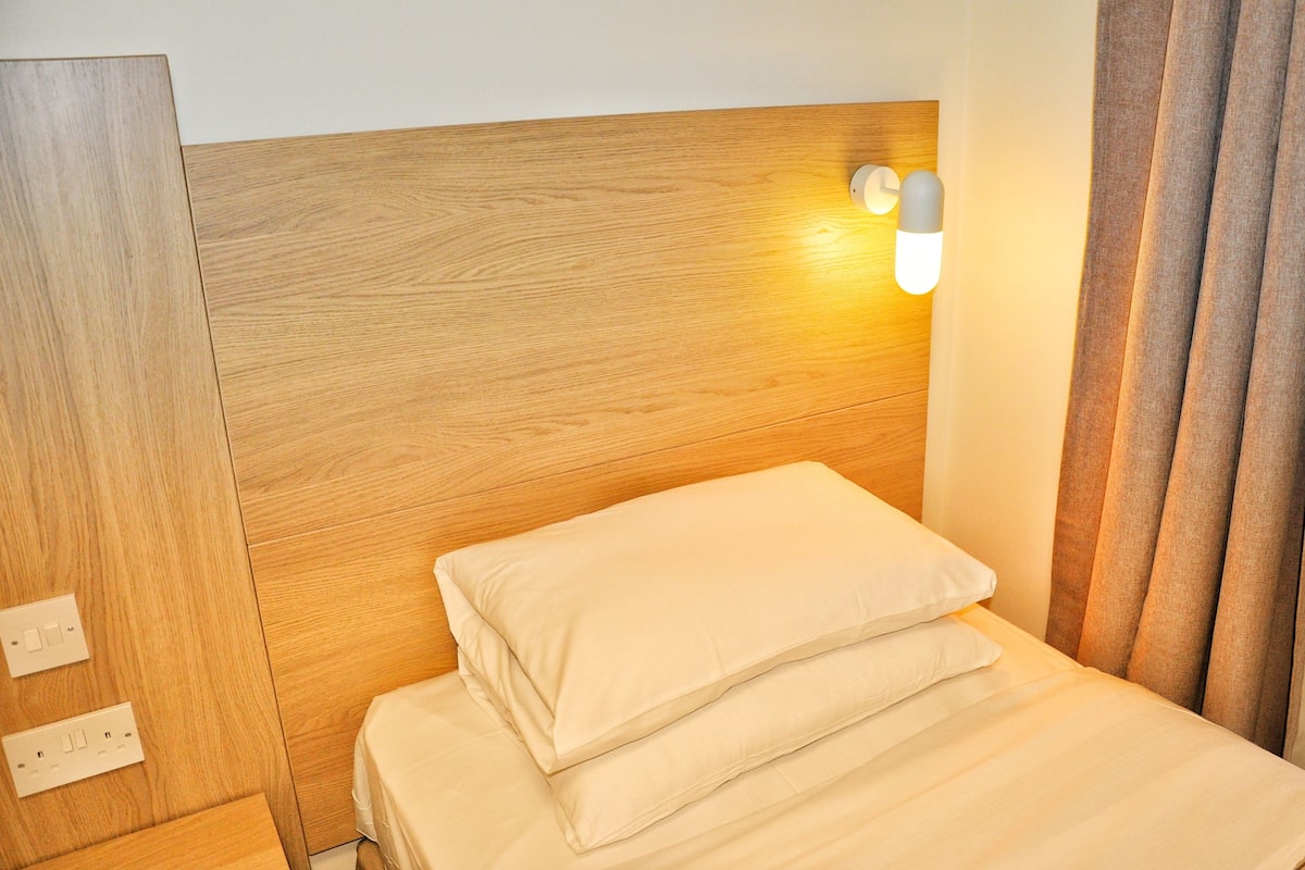 Una cama bien hecha con cabecera de madera y una lámpara de pared.