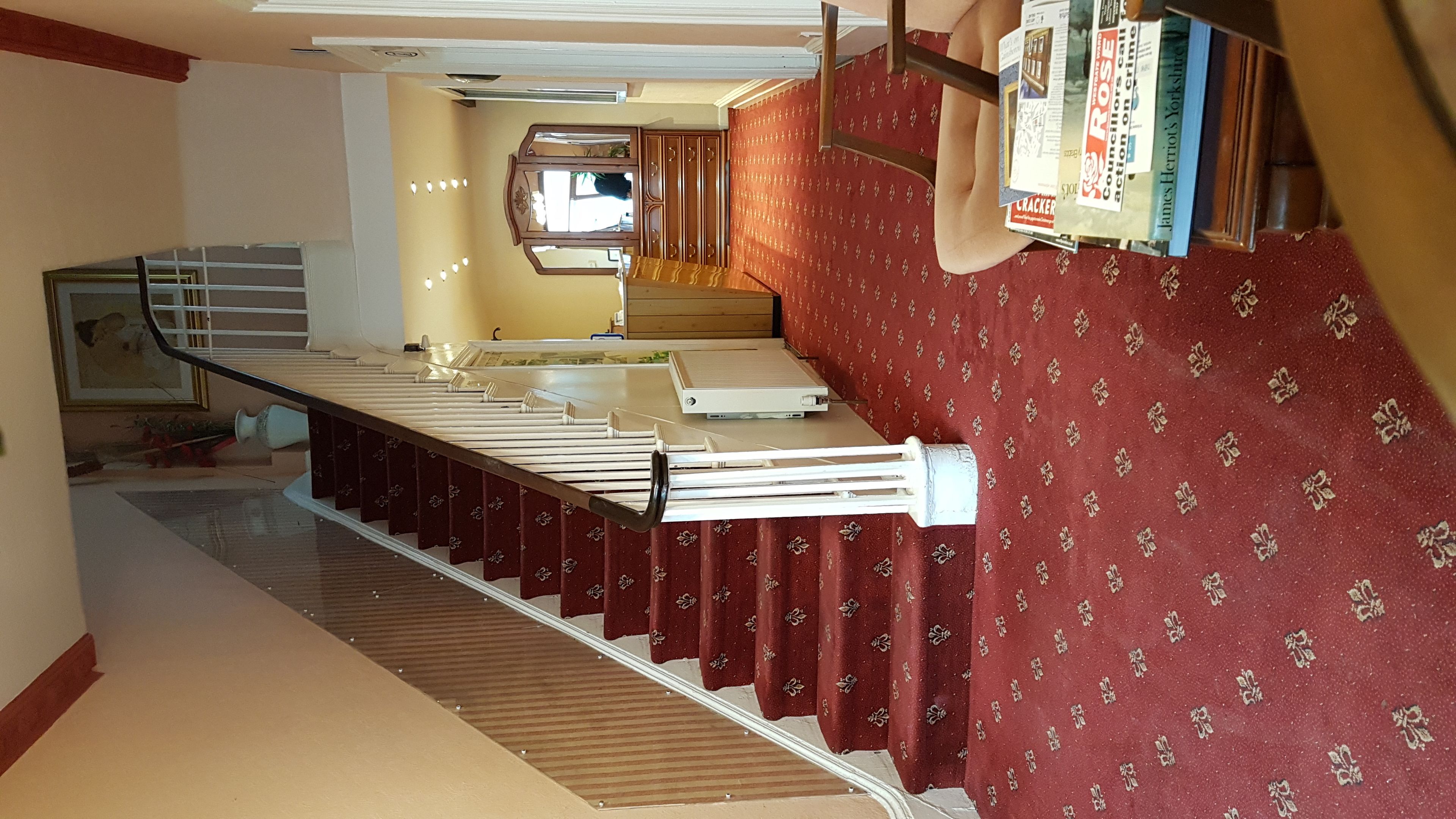 A staircase with a red patterned wall and a white handrail.
