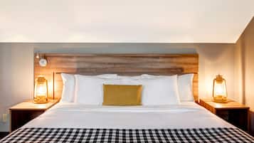 Quarto de hotel com uma cama grande, duas mesas de cabeceira com luminárias estilo lanterna, uma cabeceira de madeira e um edredom xadrez.