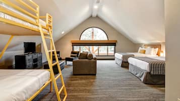 Ein geräumiges Schlafzimmer im Dachgeschoss mit Etagenbetten, einer Schlafcouch und einem großen Fenster, das natürliches Licht hereinlässt.