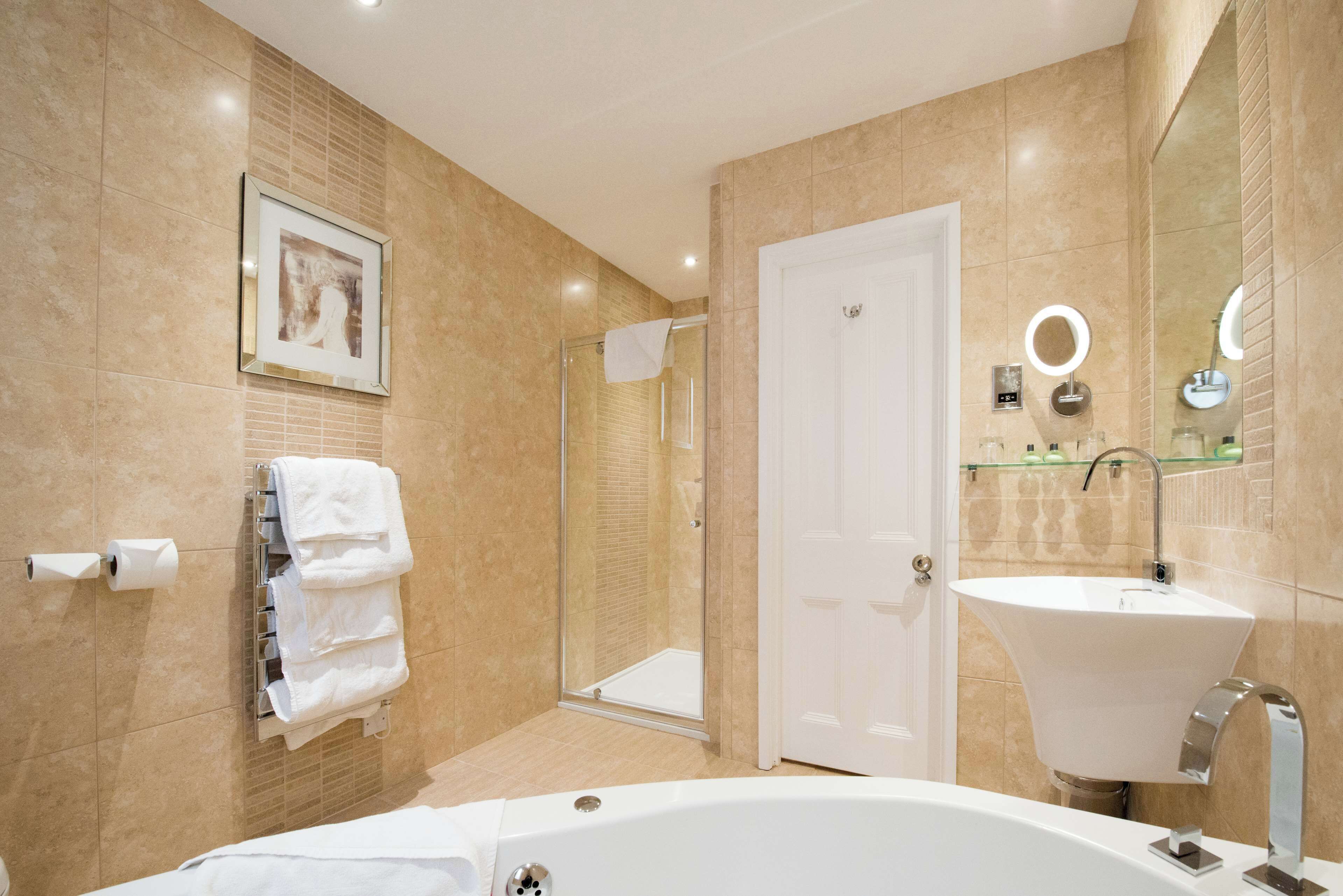 A modern bathroom with a bathtub, a sink, a glass shower enclosure, and a framed picture on the wall.
