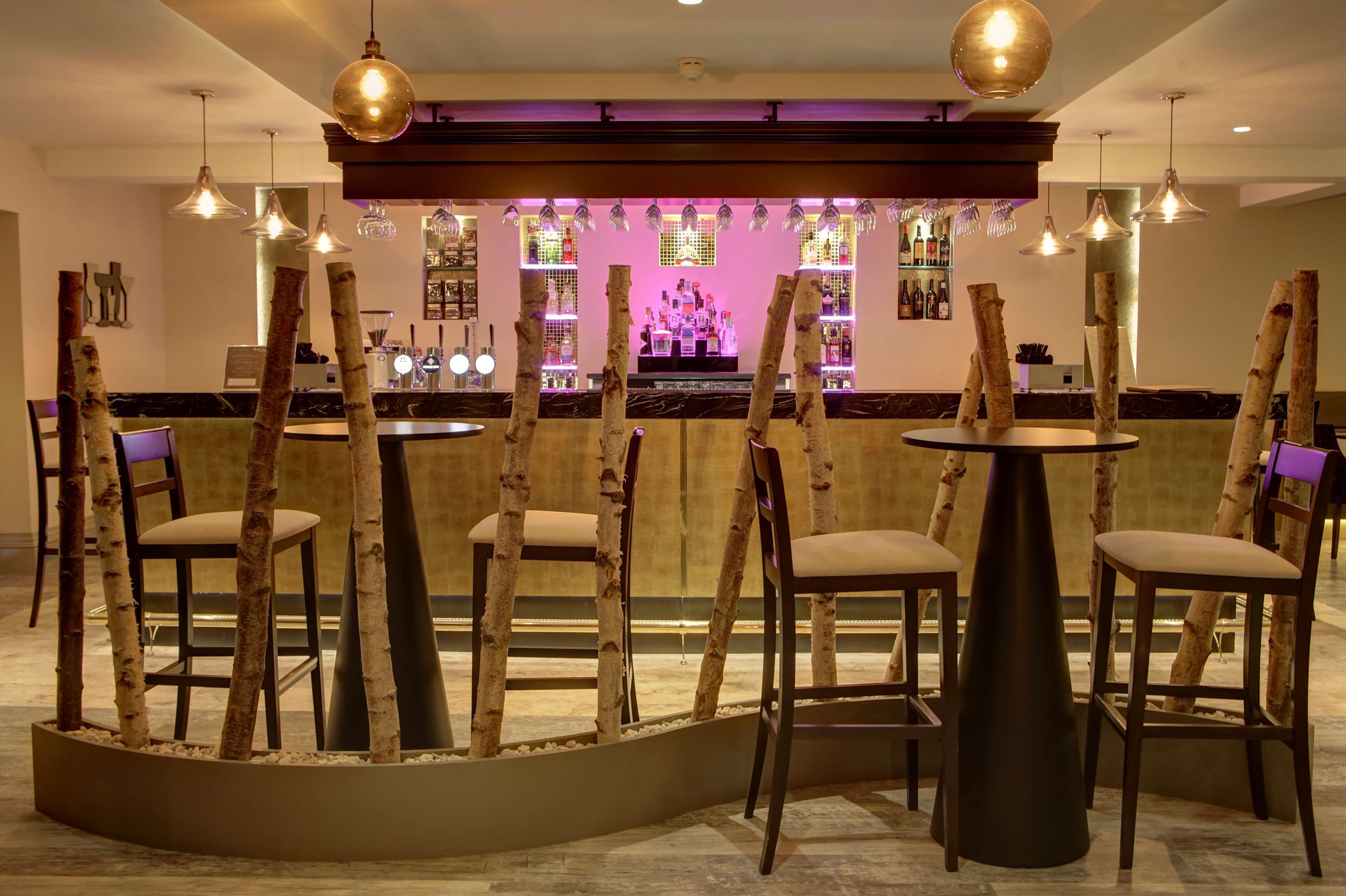 Een bar met houten stoelen en tafels, een bargedeelte en hangende吊灯
