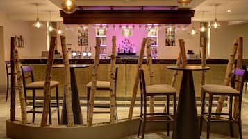 Een bar met houten stoelen en tafels, een bargedeelte en hangende吊灯