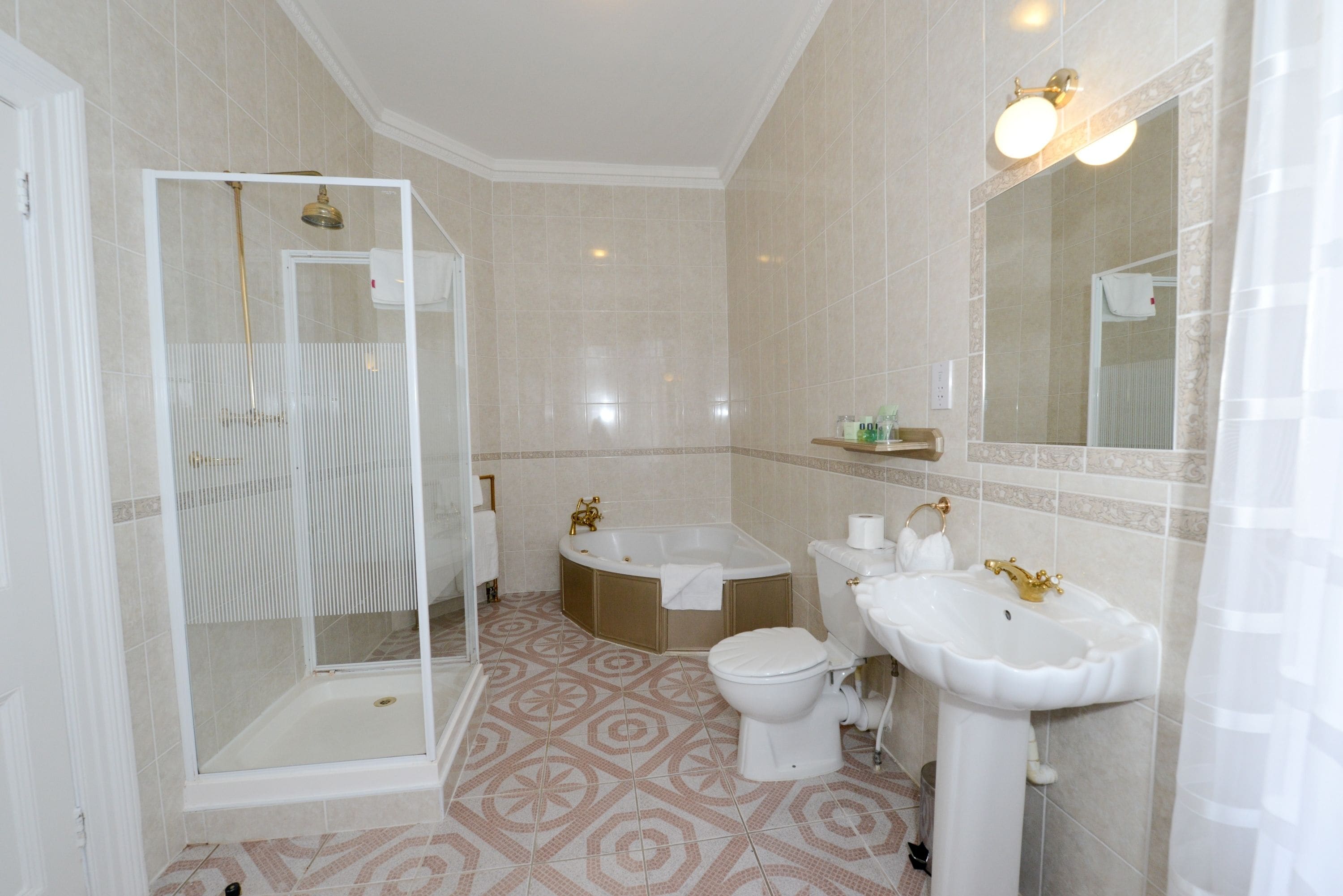A modern bathroom with a glass-enclosed shower, a freestanding bathtub, a toilet, and a pedestal sink.