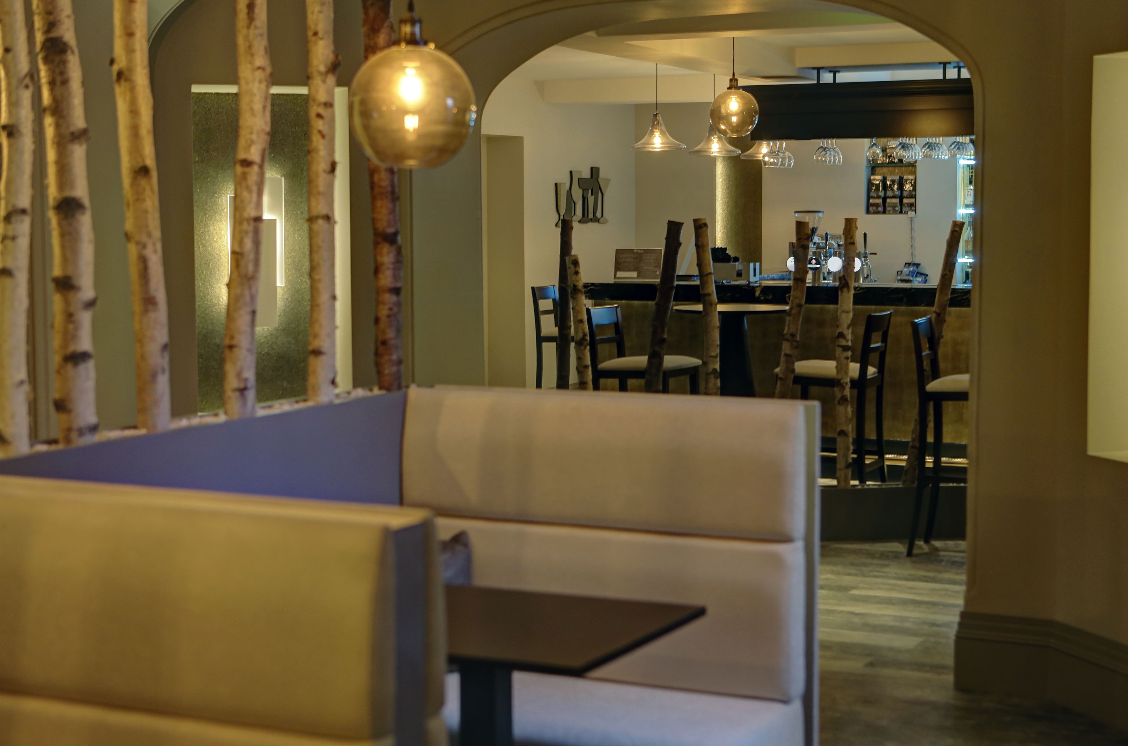 Ein gemütlicher Essbereich mit einer Sitzbank, einer Bar im Hintergrund und Pendelleuchten.
