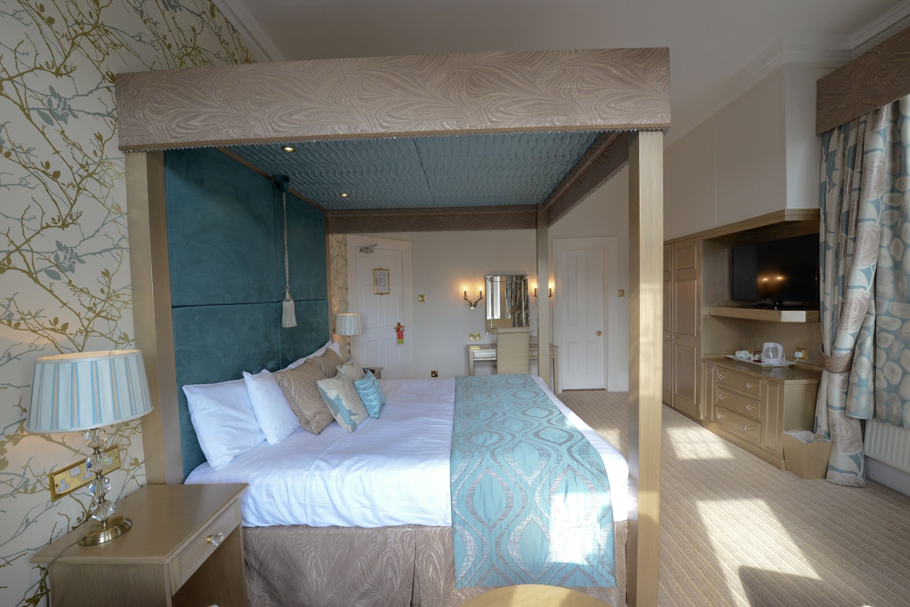 Une chambre d’hôtel avec un grand lit, un bureau, une télévision et une salle de bain visible à travers une porte ouverte.