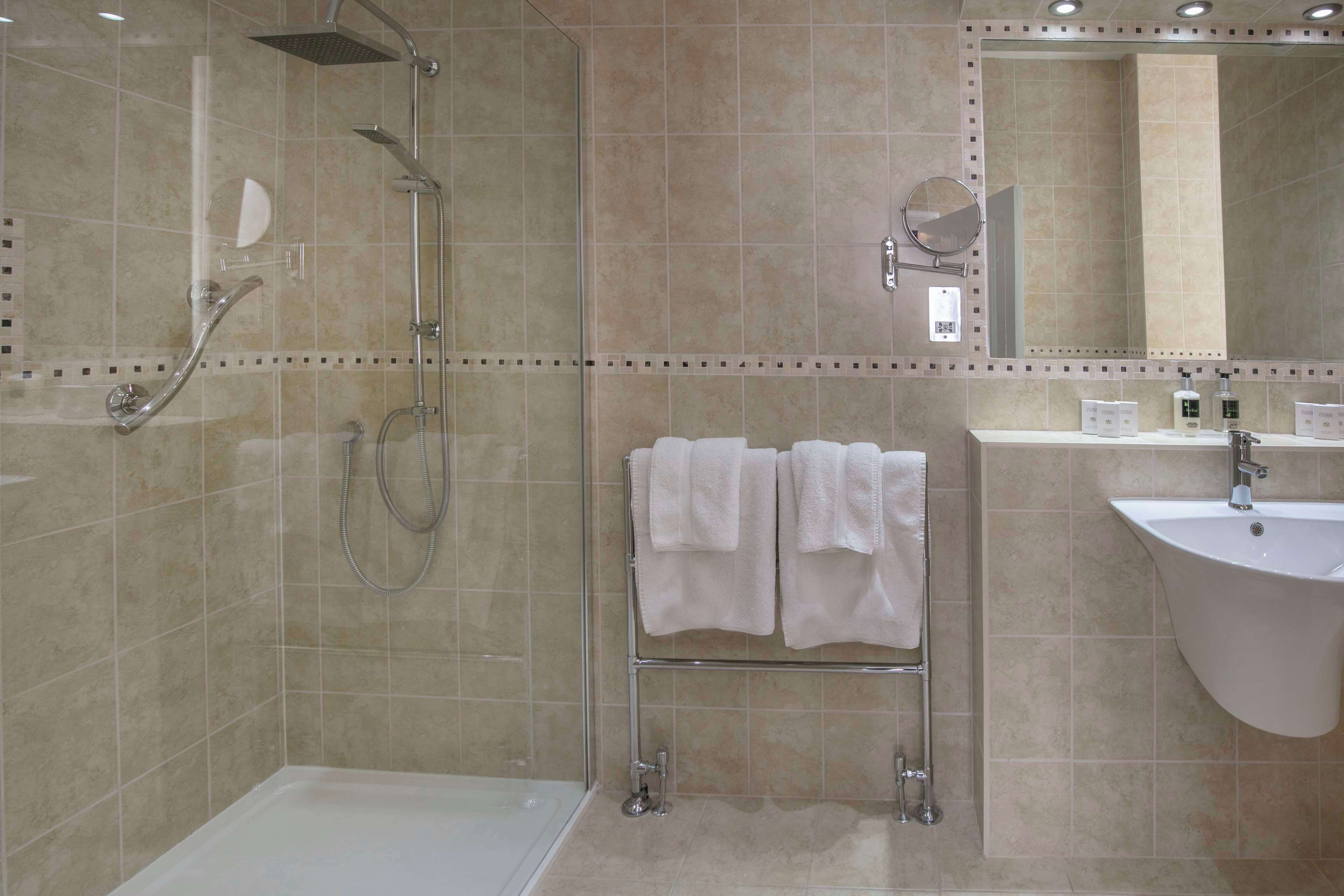 A modern bathroom with a bathtub, a shower, a sink, and a towel rack.
