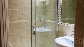 A glass-enclosed shower with a white sink and a mirror above it.