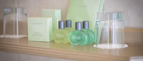 Uma bancada de banheiro com artigos de higiene pessoal, incluindo uma barra de sabão, uma garrafa de shampoo e uma garrafa de condicionador.