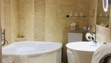A bathroom with a freestanding bathtub, a sink, and a mirror with a light.